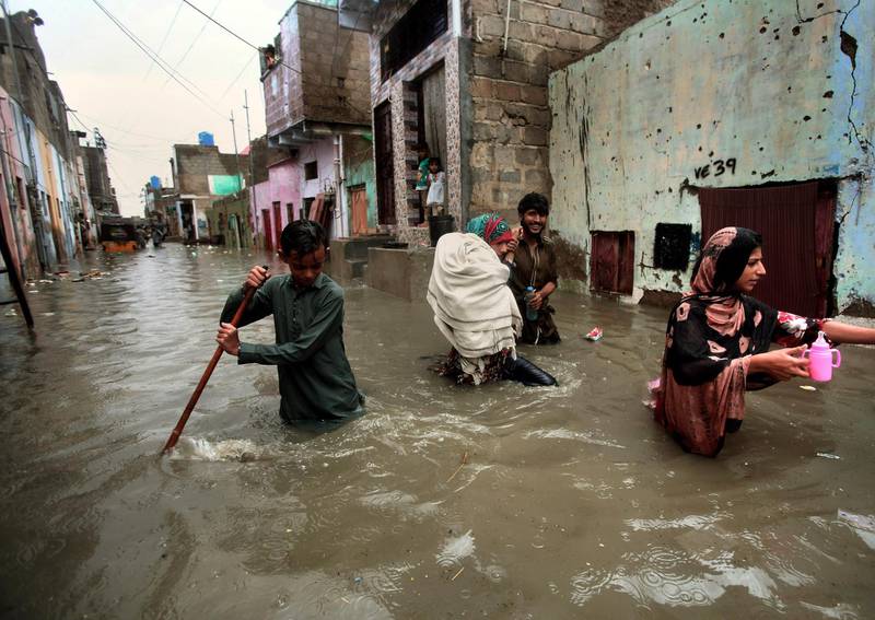 A family wades through a flooded street caused by heavy monsoon rains, in Karachi, Pakistan, Sunday, Aug. 11, 2019. Monsoon rains have inundated much of Pakistan, leaving large parts of the southern city of Karachi underwater and causing some deaths. (AP Photo/Fareed Khan)