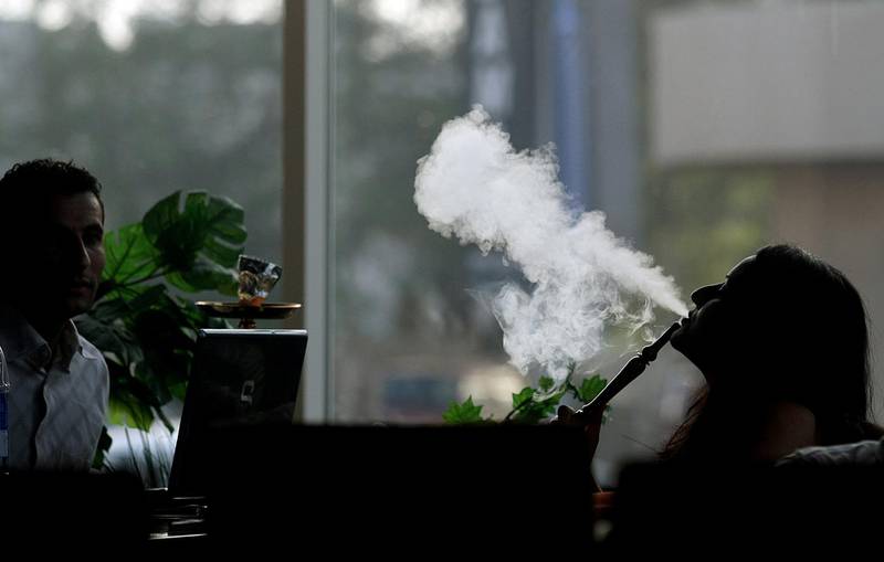 A woman smokes waterpipe (Shisha) at a cafe in Dubai on May 31, 2008. The Gulf emirate of Dubai banned the sale of tobacco to anyone under the age of 20 with immediate effect and barred young people from public areas in which smoking is allowed. The announcement was made in public advertisements in Arabic-language newspapers as part of a "Youth Without Tobacco" campaign. The campaign was launched to coincide with World No Tobacco Day on May 31. AFP PHOTO/MARWAN NAAMANI (Photo by MARWAN NAAMANI / AFP)