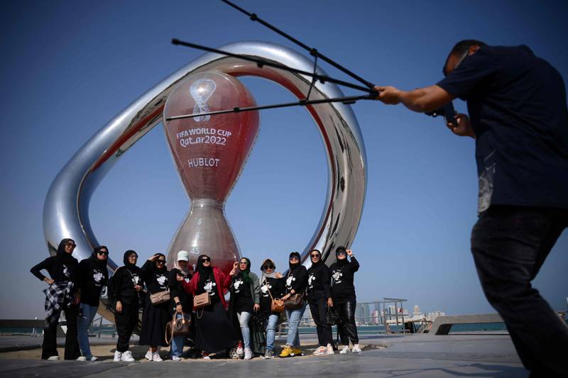 Fans pose in front of the Qatar 2022 countdown clock in Doha. AFP