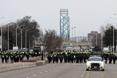 Police gather to clear protestors against Covid-19 vaccine mandates who blocked the entrance to the Ambassador Bridge in Windsor, Ontario, Canada, on February 13, 2022. - Canadian police resumed operations Sunday to clear a key US border bridge occupied by trucker-led demonstrators angry over Covid-19 restrictions, as authorities began making arrests in their bid to quell a movement that has also paralyzed downtown Ottawa. (Photo by JEFF KOWALSKY / AFP)