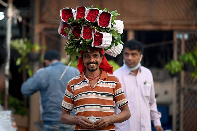 A vendor carries a bunch of roses at a flower market in New Delhi. AFP