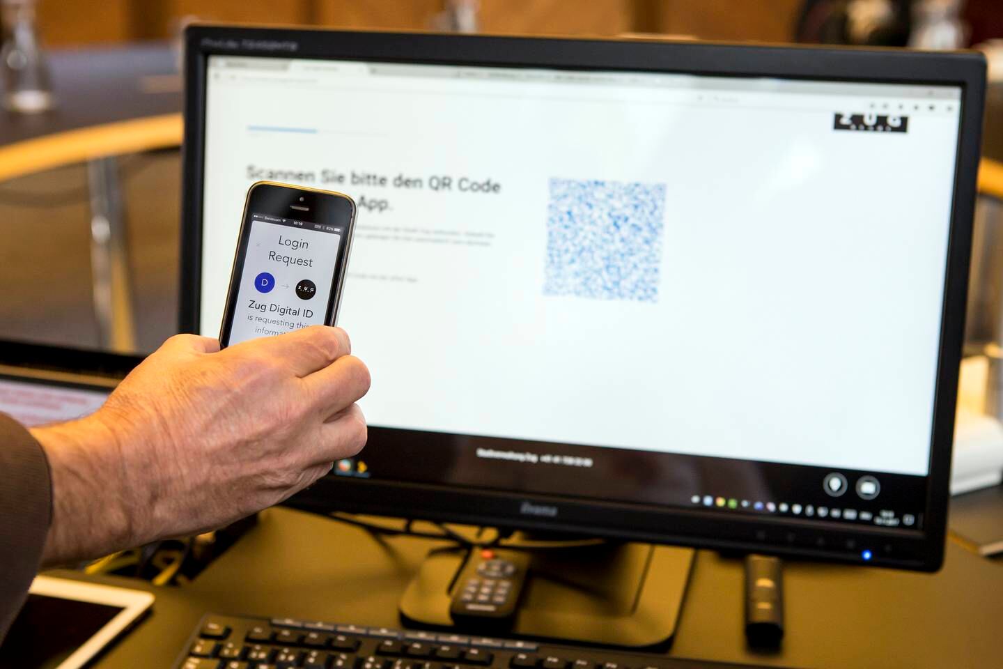 epa06330660 A mobile phone and a computer screen are seen during the demonstration of a blockchain-based digital ID in Zug, Switzerland, 15 November 2017. The city of Zug now offers all residents the opportunity to get a digital identity. This is based on an app and is linked to the Ethereum Blockchain.  EPA/ALEXANDRA WEY
