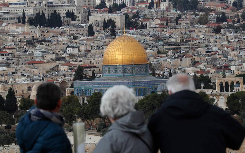 Tourists look at the Old City of Jerusalem and its Dome of the Rock mosque from the Mount of Olives on December 6, 2019.  / AFP / EMMANUEL DUNAND
