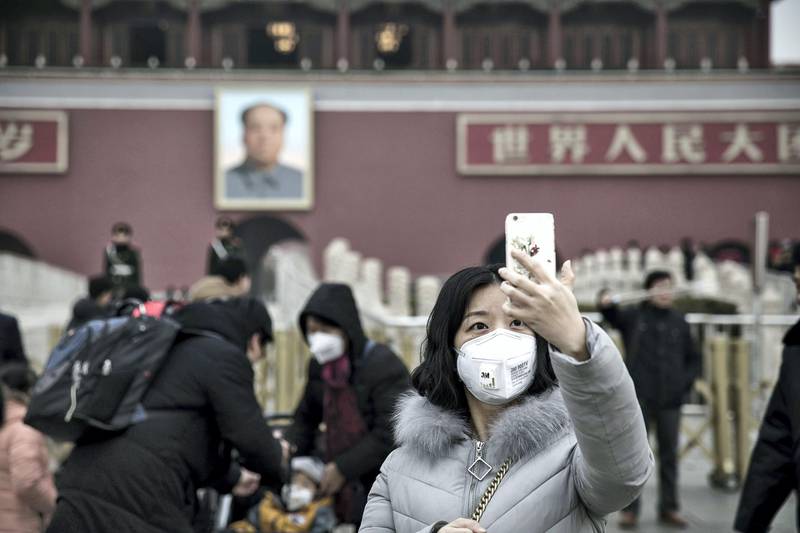 A woman wearing a face mask takes a selfie photograph in front of the Tienanmen Gate in Beijing, China, on Friday, Jan. 6, 2017. Toxic haze that settled over much of China during the last three weeks has triggered a flight reflex among residents, leading to the rising popularity of smog avoidance travel packages to far-flung locations such as Iceland and Antarctica. Photographer: Qilai Shen/Bloomberg