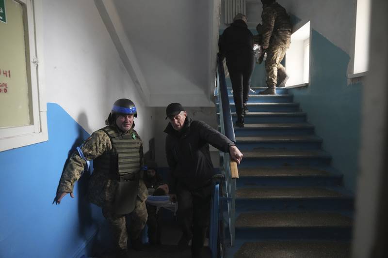A Ukrainian serviceman and a civilian carry a wounded man who was injured by shelling in a hospital in Mariupol. AP Photo