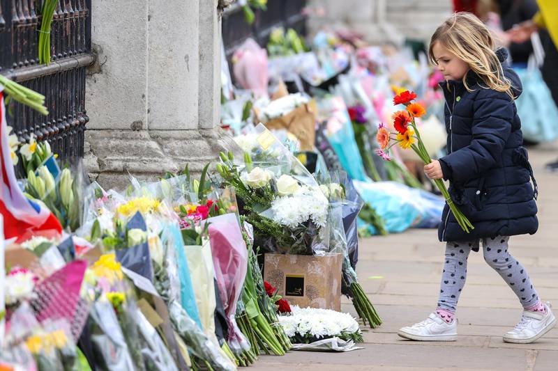 A  girl lays flowers as tribute to Prince Philip outside Buckingham Palace, in London. Getty Images