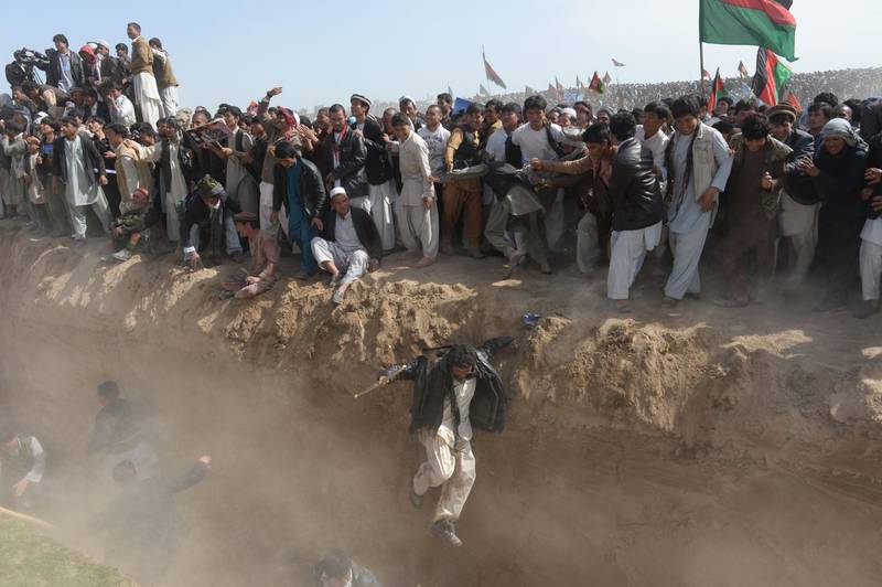 Supporters of presidential candidate Ashraf Ghani jump to cross a ditch as they leave after a gathering on the outskirts of Kunduz province, north of Kabul. March 19, 2014. Shah Marai / AFP
