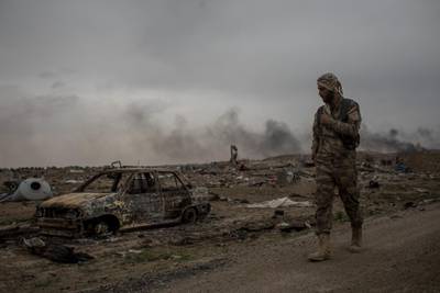 BAGHOUZ, SYRIA - MARCH 24: A Syrian Democratic Forces (SDF) fighter walks past destroyed vehicles in the final ISIL encampment on March 24, 2019 in Baghouz, Syria. The Kurdish-led and American-backed Syrian Defense Forces (SDF) declared on Saturday the "100 percent territorial defeat" of the so-called Islamic State, also known as ISIS or ISIL. The group once controlled vast areas across Syria and Iraq, a population of up to 12 million, and a "caliphate" that drew tens of thousands of foreign nationals to join its ranks.  (Photo by Chris McGrath/Getty Images) ***BESTPIX***