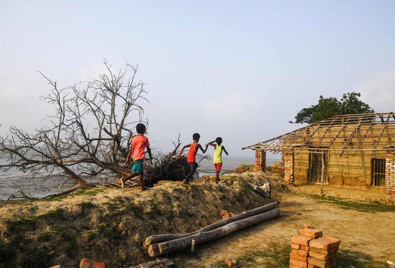 In this photo taken on May 18, 2019, Indian children play on the coast affected by erosion on the Ghoramara island around 110 km south of Kolkata, ahead of the 7th and final phase of India's general election. Thousands of former Ghoramara residents have already moved to Sagar, a bigger island in the delta, or moved to Kakdwip on the mainland in the last few years. Roughly half of the island has disappeared to rising water levels, erosion and changing weather patterns of the eco-sensitive delta zone in the last three decades. - To go with story 'INDIA-VOTING-ELECTION-ENVIRONMENT-CLIMATE' by Bhuvan Bagga
 / AFP / DIBYANGSHU SARKAR / To go with story 'INDIA-VOTING-ELECTION-ENVIRONMENT-CLIMATE' by Bhuvan Bagga
