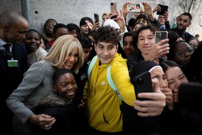 Brigitte Macron, the wife of the French President, poses with pupils for a selfie as she visits the public French language school, in Bern. AFP