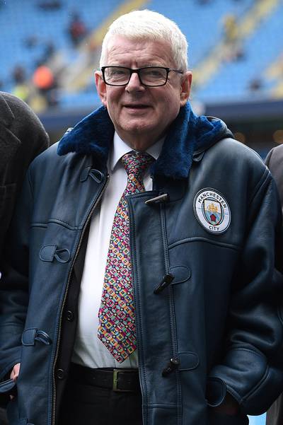 BBC commenatator John Motson reacts after being presented with a Manchester City branded coat ahead of the English Premier League football match between Manchester City and Burnley at the Etihad Stadium in Manchester, north west England, on October 21, 2017. / AFP PHOTO / Oli SCARFF / RESTRICTED TO EDITORIAL USE. No use with unauthorized audio, video, data, fixture lists, club/league logos or 'live' services. Online in-match use limited to 75 images, no video emulation. No use in betting, games or single club/league/player publications.  / 