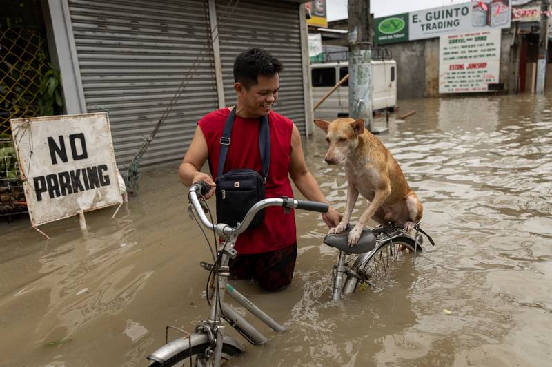 A-Jhay Celis, 35, wades through flood water with his dog Domeng, following heavy rains brought by tropical storm Nalgae, in Imus, Cavite province, Philippines. Reuters