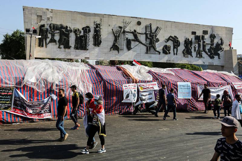 Iraqi protesters walk past sit-in tents erected at an anti-government demonstration in the capital Baghdad's Tahrir Square.  AFP