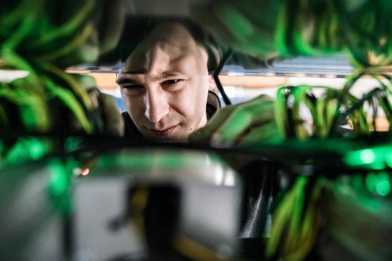 Sebastian Kastner, lead engineer at HydroMiner GmbH, handles cable connections between cryptocurrency mining rigs on racks at the company's mining facility near Waidhofen an der Ybbs, Austria, on Friday, Jan. 19, 2018. HydroMiner, the Austrian cryptocurrency miner that mines bitcoins with green energy, is weighing an initial public offering to fund an expansion outside its home country. Photographer: Akos Stiller/Bloomberg