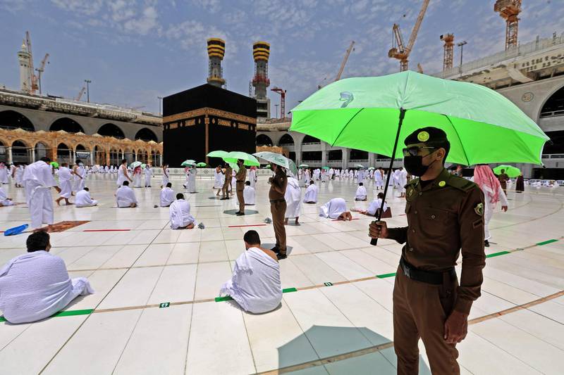 Members of the Saudi security forces with parasols stand guard as worshippers pray around the Kaaba in Makkah. AFP