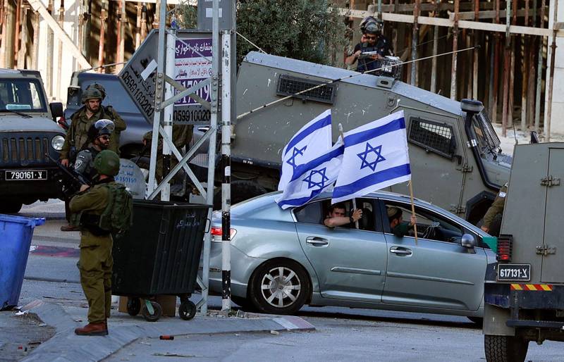 Israeli security forces look on as settlers enter Hawara. AFP