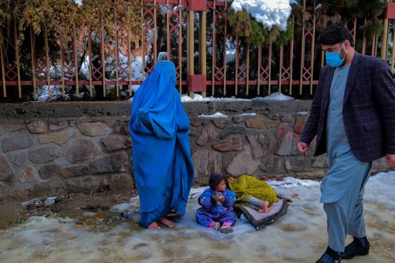 An Afghan woman with two children begs for alms in the snow in Kabul. EPA