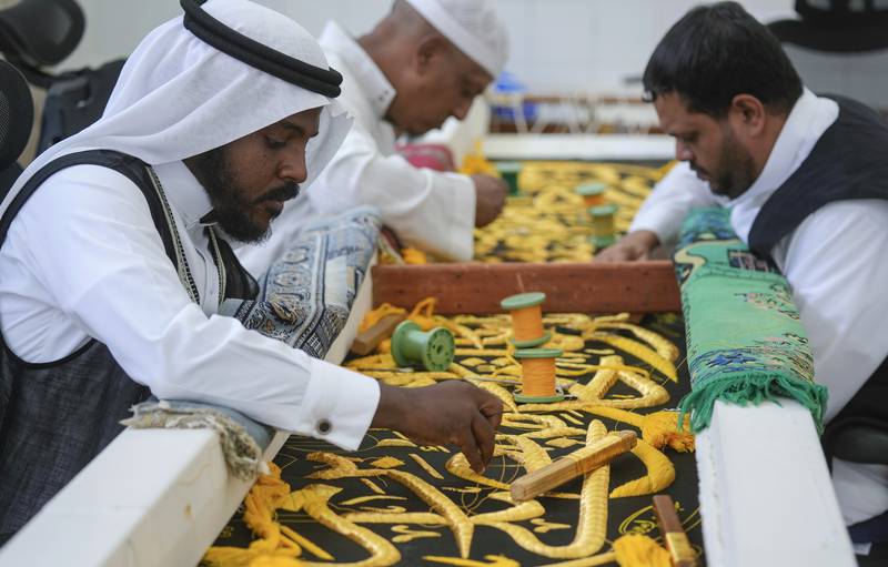 Saudi workers put the final touches to the kiswa, the drape that covers the Kaaba, a cube-shaped structure at the heart the Grand Mosque, in Makkah. AP