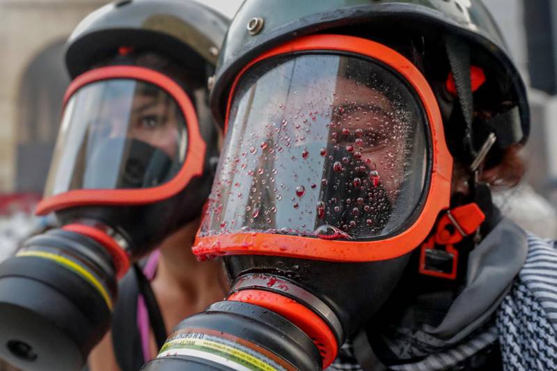 Activists help an anti-government protester with her tear gas mask covered in blood after being beaten by riot policemen near Parliament Square. AP