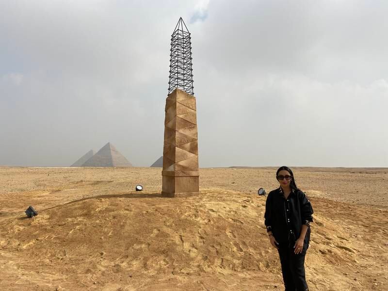 Zeinab Alhashemi stands in front of her artwork, 'The Unfinished Obelisk,' which is part of her 'Camoulflage' series that began in 2015. Nada El Sawy / The National