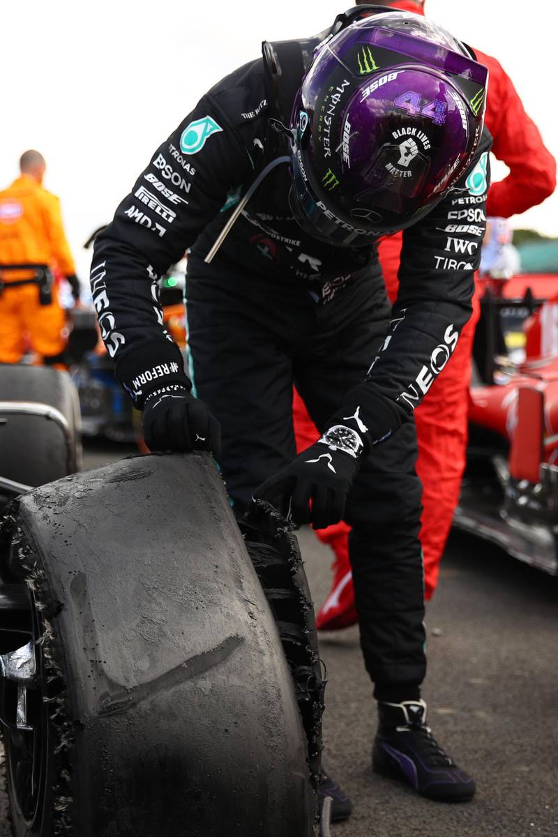 Lewis Hamilton inspects his punctured tyre after victory in the British GP. AFP