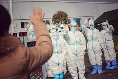 Medical staff members wave to a recovered patient (foreground L) at Leishenshan Hospital, the makeshift hospital for the COVID-19 coronavirus patients, in Wuhan in China's central Hubei province.  AFP