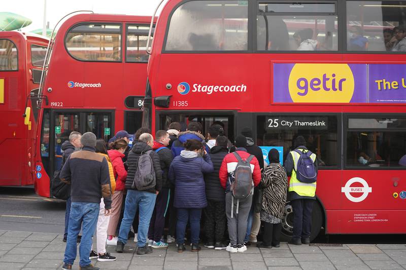 People queue to board buses outside Stratford Tube station. PA
