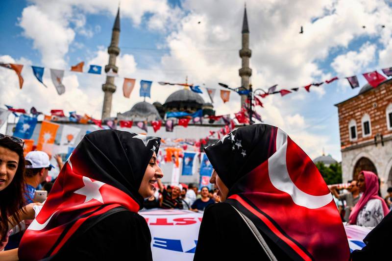 Two young women attend a presidential campaign happening at a pro-Erdogan supporters' kiosk in Istanbul on June 19, 2018.  Under Erdogan, Turkey has sought to rebuild its Ottoman-era influence in the Middle East, notably in Syria and Iraq as well as the Balkans and also Africa. In presidential and legislative polls on June 24, Erdogan and his party will face the biggest test at the ballot box to their one-and-a-half-decade grip on power. / AFP / Aris MESSINIS
