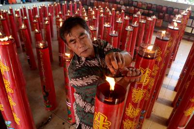 An Indonesian worker cleans candles at the Gayatri temple in Cilodong, West Java. EPA