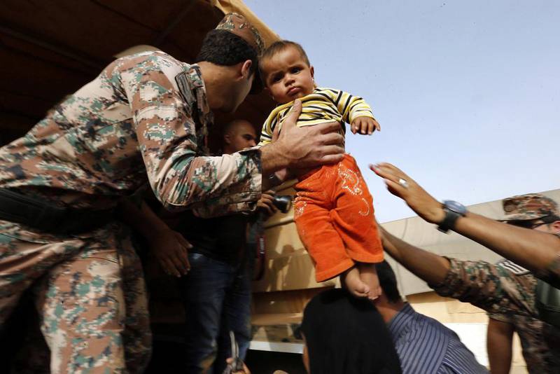 A Jordanian soldier helps a Syrian refugee family to board an army vehicle in Al Ruqban border area. Muhammad Hamed / Reuters