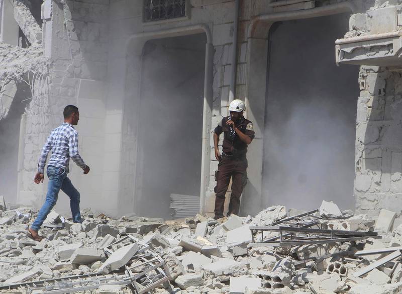 This photo provided by the Syrian Civil Defense group known as the White Helmets, shows a civil defense worker speaking on his radio next to a building that was attacked by a Syrian government airstrike, in Hobeit village, near Idlib, Syria, Sunday, Sept. 9, 2018. The White Helmets and a conflict monitoring group said Sunday that government and Russian forces have resumed their bombing of the opposition's last stretch of territory in the country, killing an infant girl and damaging a hospital. (Syrian Civil Defense White Helmets via AP)