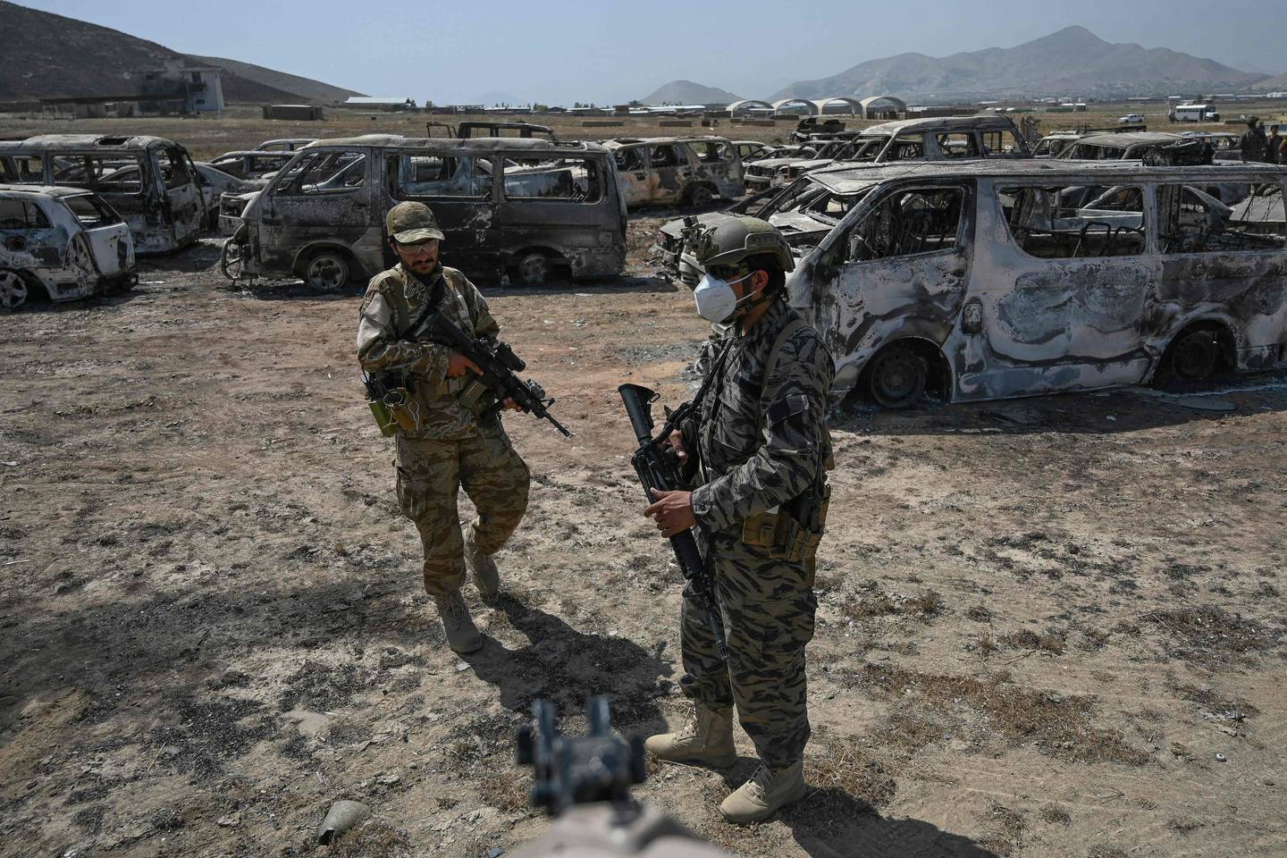 Members of the Taliban Badri 313 military unit stand beside damaged vehicles kept near the destroyed Central Intelligence Agency (CIA) base in Deh Sabz district. AFP
