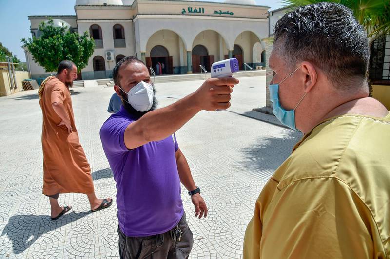An Algerian volunteer checks the temperature of men arriving to perform the noon prayer at the El Fateh mosque in the El Afia de Kouba neighbourhood of the capital Algiers. AFP