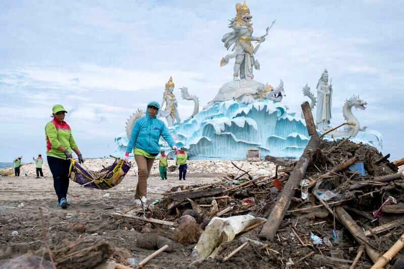 Workers clean debris and plastic waste on a beach in Bali, Indonesia. EPA

