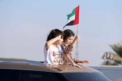 Proud siblings wave the national flag on the Corniche in Abu Dhabi. Khushnum Bhandari / The National