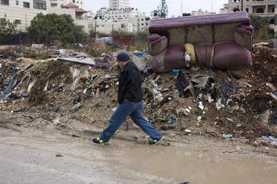 Basam Maswadeh, Kufr Aqab's village council head, is pictured trying to cross a road flooded with sewage and garbage on October 29, 2015. Heidi Levine for The National.