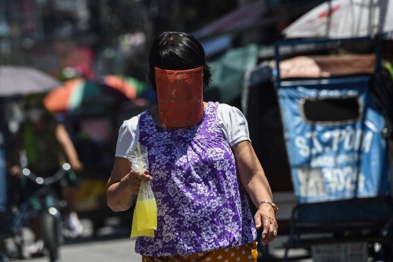 A resident wearing a face shield walks along a street in a Manila neighbourhood under strict quarantine measures. AFP / Ted ALJIBE