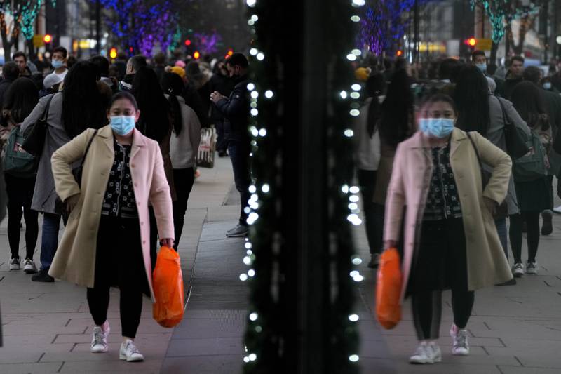 A shopper wearing a mask is reflected in a window as she walks down Oxford Street in London. Daily numbers of Covid-19 cases have passed 100,000 for the first time in the UK. AP Photo