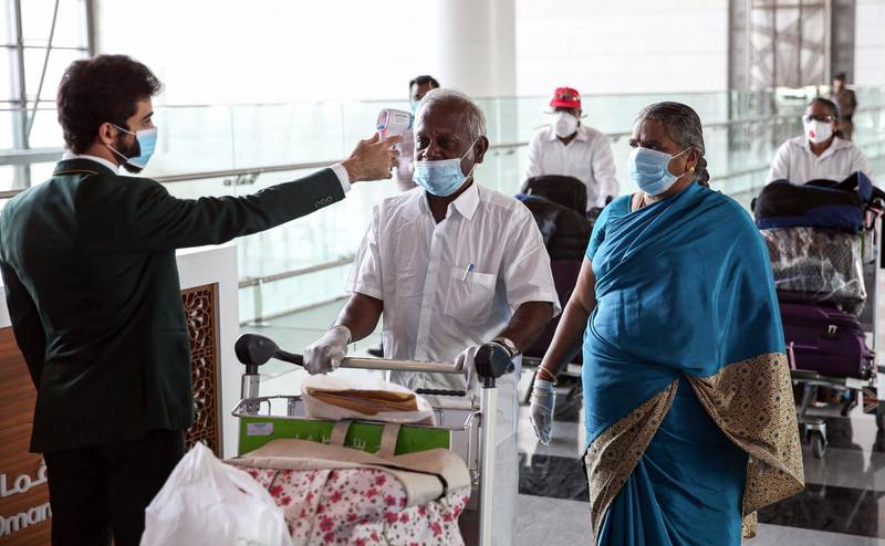 Indian nationals residing in Oman, wearing face masks due to the coronavirus pandemic, have their body temperatures measured at a terminal in Muscat International Airport ahead of their repatriation flight from the Omani capital, on May 12, 2020.  AFP