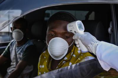 A staff member of the Ministry of Health measures the temperature of drivers and passengers during the testing of the COVID-19 Coronavirus on the highway in Nakuru, Kenya.  AFP