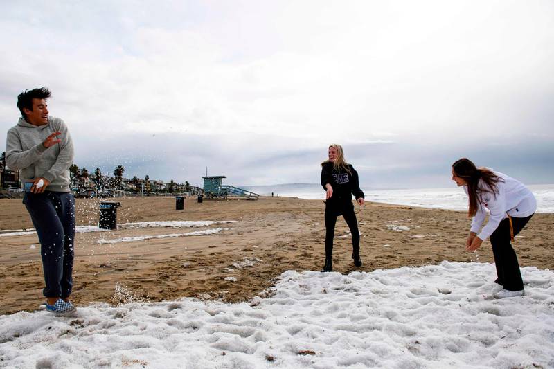 Teenagers play with hail on the beach following winter storms that blanketed the region with rain, snow, and hail in Manhattan Beach, California. AFP