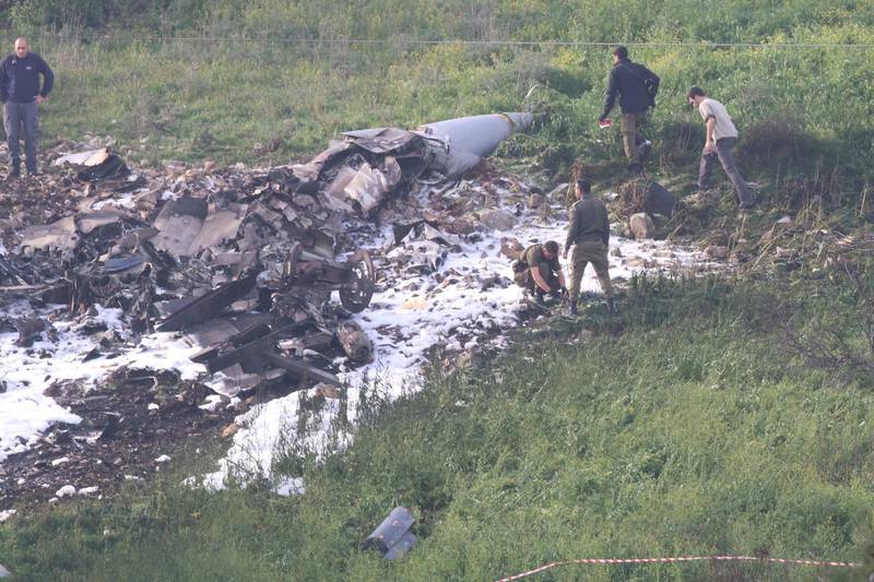Israeli security forces walk next to the remains of an F-16 warplane near the village of Harduf, Israel on February 10, 2018. Herzie Shapira / Reuters