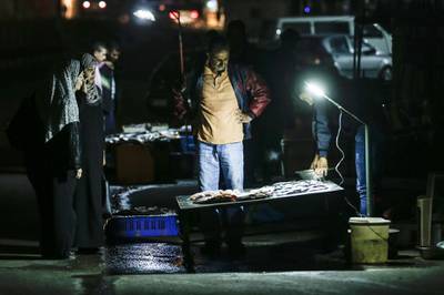 Palestinians gather at a stall to buy fish in Gaza City. AFP