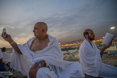 A Muslim pilgrim reads the Quran as another pilgrim takes a photo. AP Photo