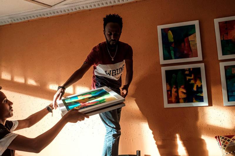 A person hands framed paintings to Eritrean painter Noah Mulubrhan as he prepares an exhibition in a local coffee shop in Addis Ababa. AFP