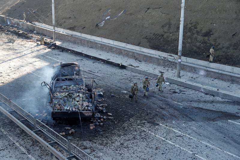 Ukrainian soldiers walk by a damaged vehicle, at the site of fighting with Russian troops, in Kiev. Reuters