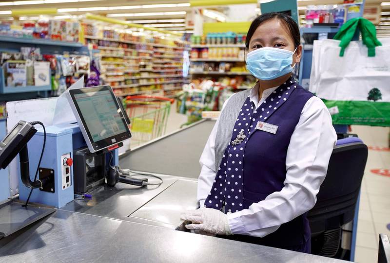 Bandana Rai, from Nepal, is a cashier at Lulu Hypermarket, Khalidiyah Mall in Abu Dhabi. It is among the few stores allowed open to ensure shoppers can get essentials. She says she feels safe because the company has installed thermal scanners and has given staff gloves and masks. Victor Besa / The National