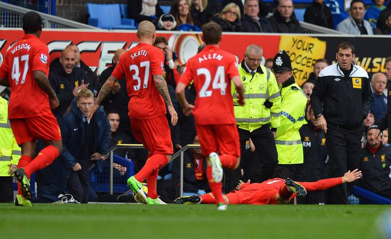 Liverpool's Uruguayan striker Luis Suarez (R) dives in front of the Everton bench as Everton's Scottish manager David Moyes (2nd L) looks on after Liverpool take the lead in the English Premier League football match between Everton and Liverpool at Goodison Park in Liverpool, north-west England on October 28, 2012. Earlier this week David Moyes urged referee Andre Marriner not to fall for the play-acting of Liverpool striker Luis Suarez. AFP PHOTO/PAUL ELLIS

RESTRICTED TO EDITORIAL USE. No use with unauthorized audio, video, data, fixture lists, club/league logos or “live” services. Online in-match use limited to 45 images, no video emulation. No use in betting, games or single club/league/player publications (Photo by PAUL ELLIS / AFP)