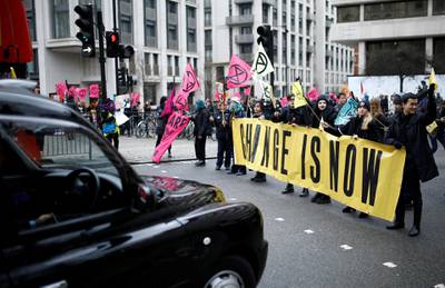 A taxi and a bus wait as Extinction Rebellion activists block a road, holding signs, during protest outside a venue for London Fashion Week, Britain February 15, 2020. REUTERS/Henry Nicholls