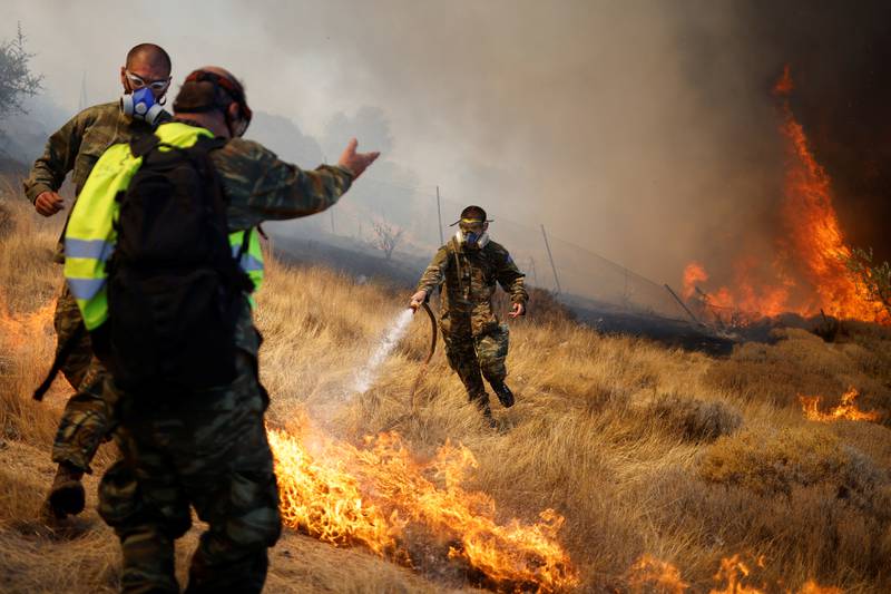 Volunteers try to extinguish a wildfire burning in the village of Markati, near Athens, Greece.